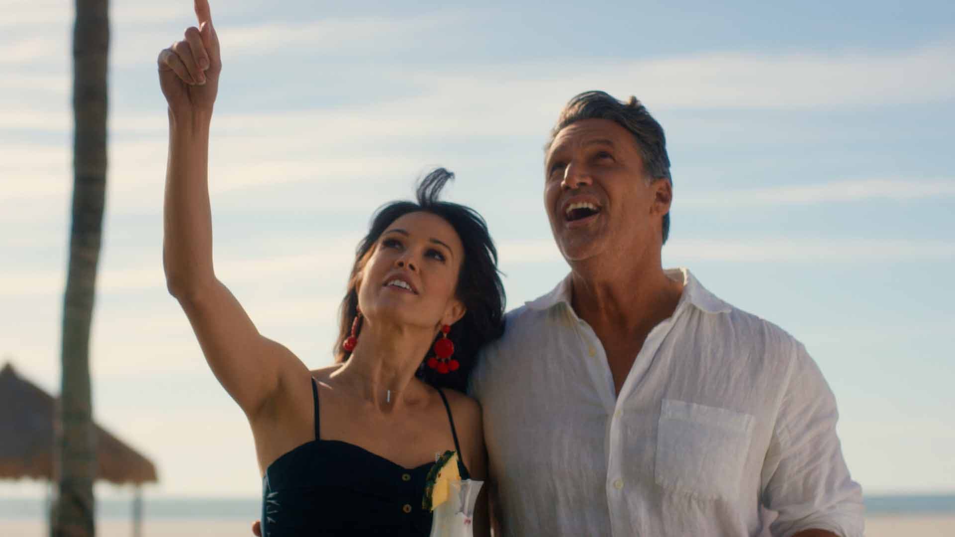 Couple on the beach pointing skyward