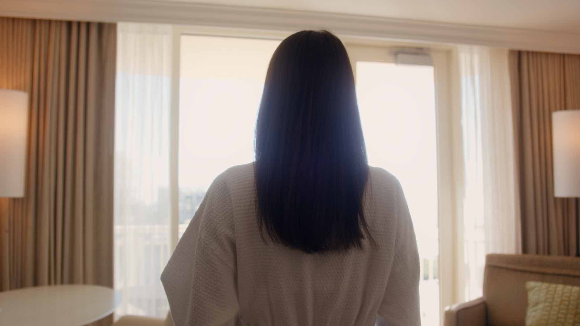 Guest in robe looking out a JW Marriott suite window