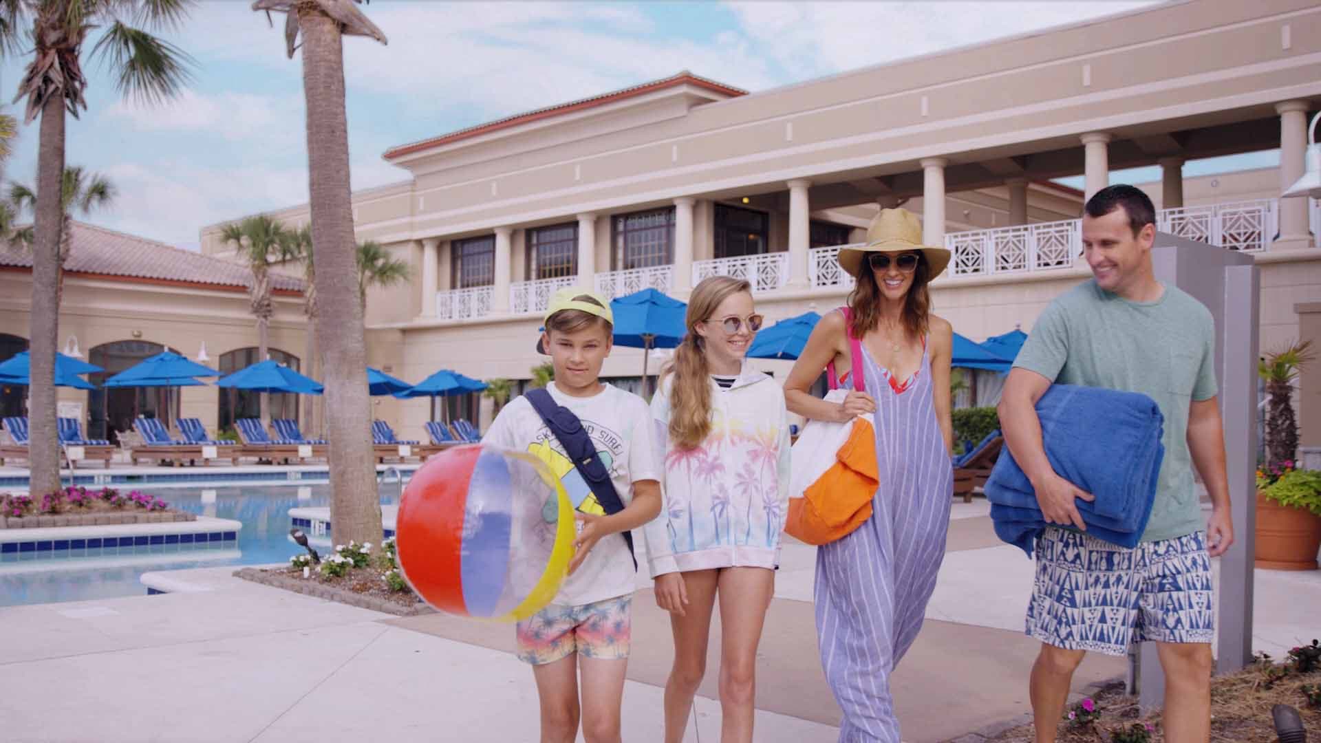 Family with beach ball walking the poolside path at Myrtle Beach Marriott
